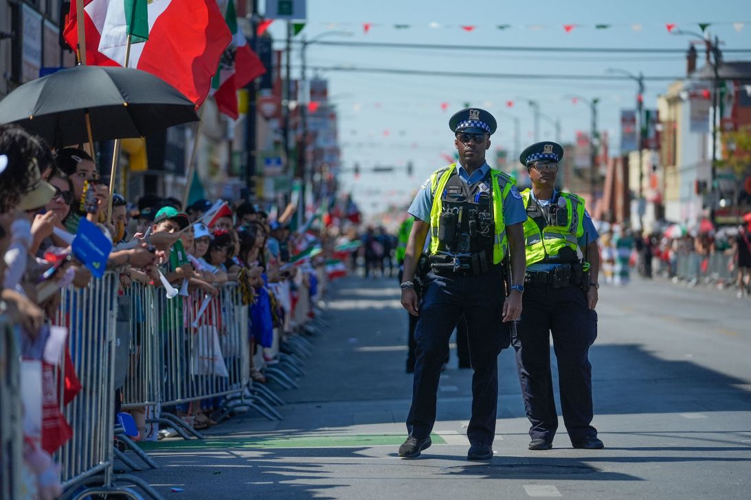 Police officers stand by as people watch the Mexican Independence Day Parade in Chicago's Little Village neighborhood.