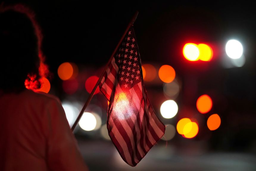 A person holds an American flag before a procession after multiple police officers were shot and killed on Wednesday.