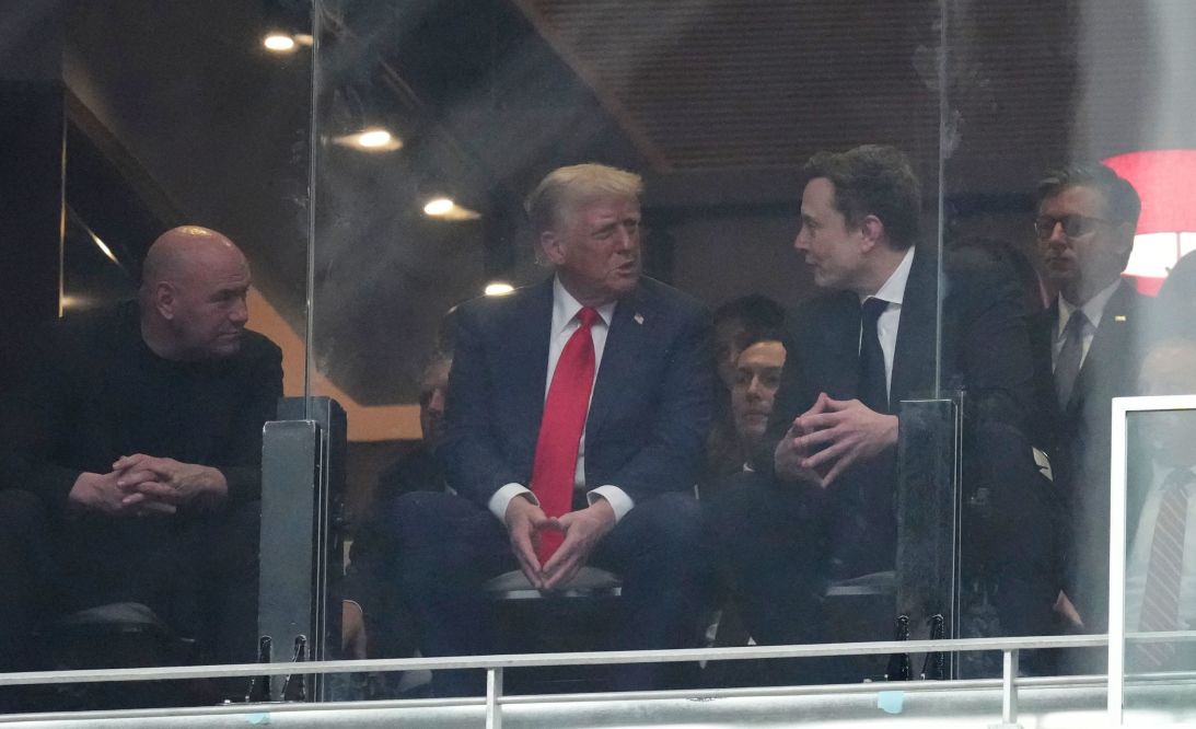From left, Dana White, President Donald Trump, Elon Musk and House Speaker Mike Johnson, talk at a memorial for Charlie Kirk in Glendale, Arizona, on Sunday.