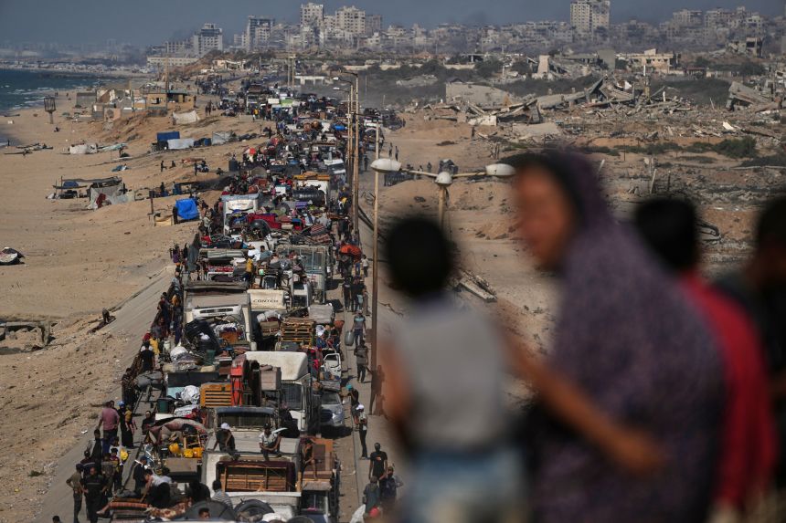 Displaced Palestinians flee the northern Gaza Strip, carrying their belongings along the coastal road near Wadi, Gaza, on September 23