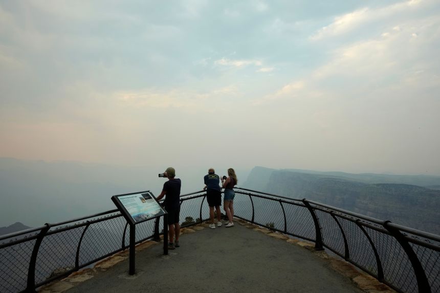 Smoke from the Dragon Bravo Fire moves over the Grand Canyon from the North Rim blocking the view for tourists at the Desert View overlook, in Grand Canyon National Park, on July 14.
