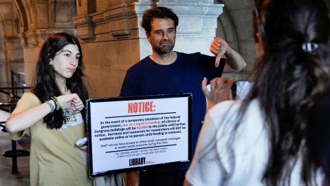 People take photos with a sign announcing that the Library of Congress is closed, on the first day of a partial government shutdown, Wednesday, Oct. 1, 2025, in Washington. (AP Photo/Julia Demaree Nikhinson)
