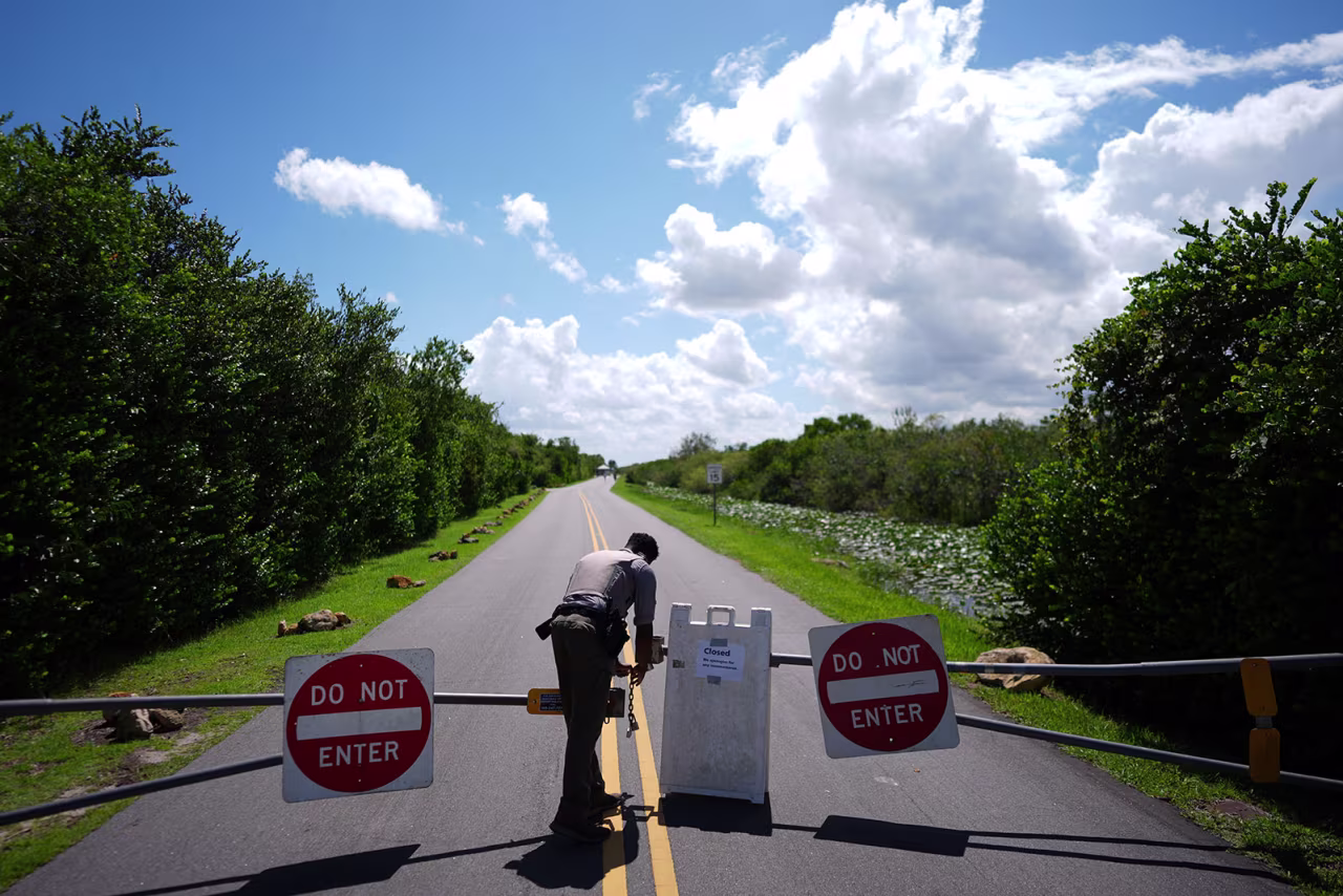 National Park Service law enforcement ranger Greg Freeman opens a locked gate closing vehicle access to the Shark Valley section of Florida's Everglades National Park, as he drives into the park, on Wednesday.