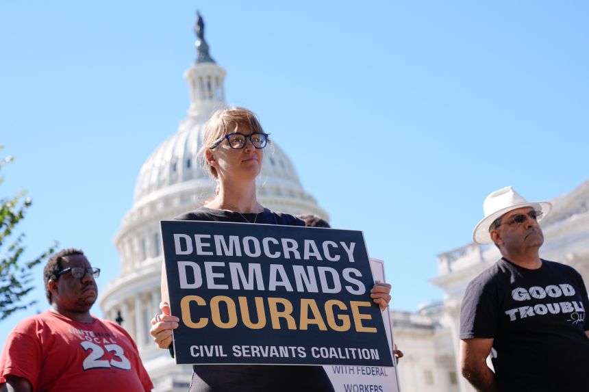 A protester holds a sign as they listen during a news conference by Democrats, Wednesday, October. 1, on Capitol Hill in Washington, DC.