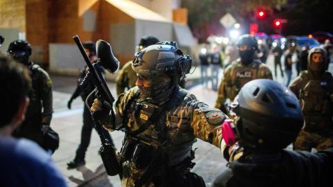 Police and Federal officers stand guard an area by the U.S. Immigration and Customs Enforcement facility in Portland, Ore. on Sunday, October 5, 2025.