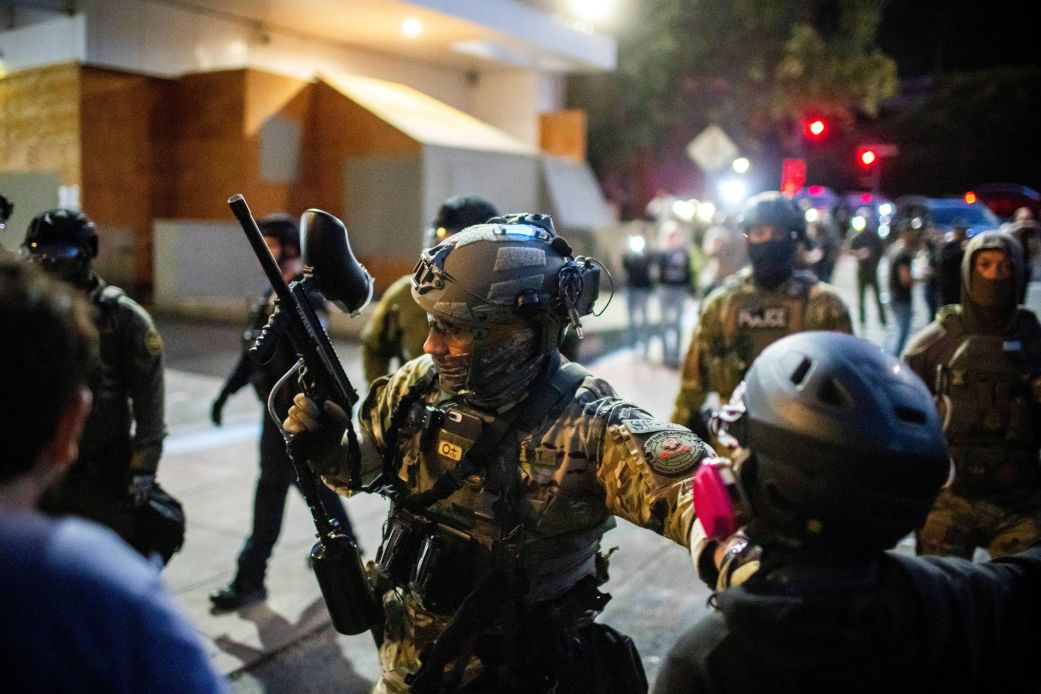 Police and Federal officers stand guard an area by the U.S. Immigration and Customs Enforcement facility in Portland, Ore. on Sunday, October 5, 2025.
