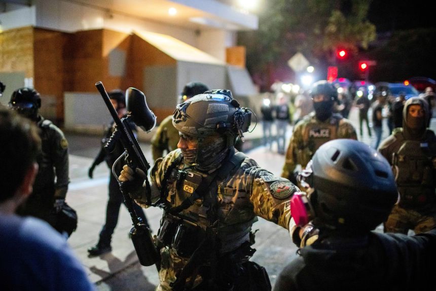 Police and federal officers stand guard at a US. Immigration and Customs Enforcement facility in Portland on Sunday, October 5, 2025.
