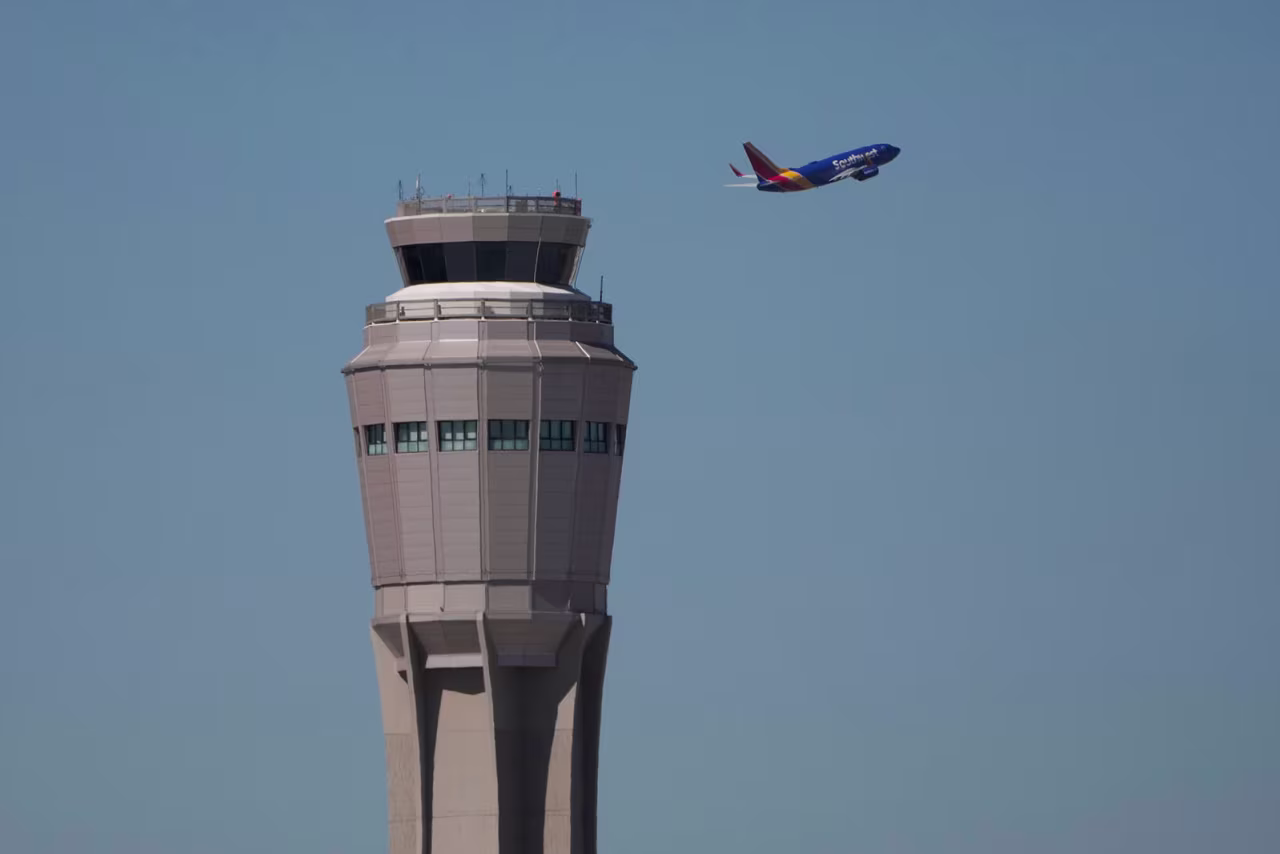 A plane takes off near the air traffic control tower at Harry Reid International Airport, Tuesday, Oct. 7, 2025, in Las Vegas. (AP Photo/John Locher)