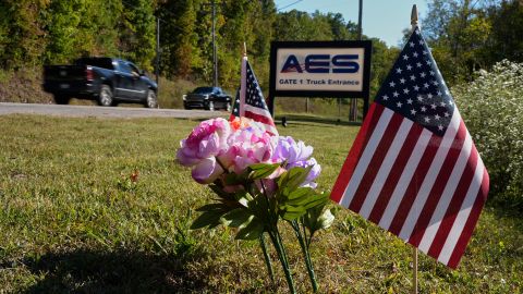 Flowers and flags rest at the entrance to Accurate Energetic Systems after an explosion on Friday, killed 16 people in McEwen, Tenn. Sunday, Oct. 12, 2025. (AP Photo/George Walker IV)