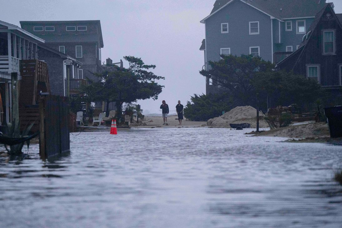 People look out at a flooded road in the midst of a storm on October 12, 2025, in Buxton, North Carolina.