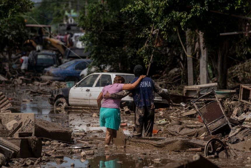 A Marine helps a woman cross a flooded street in Poza Rica in Veracruz state, Mexico, on Sunday, October 12.