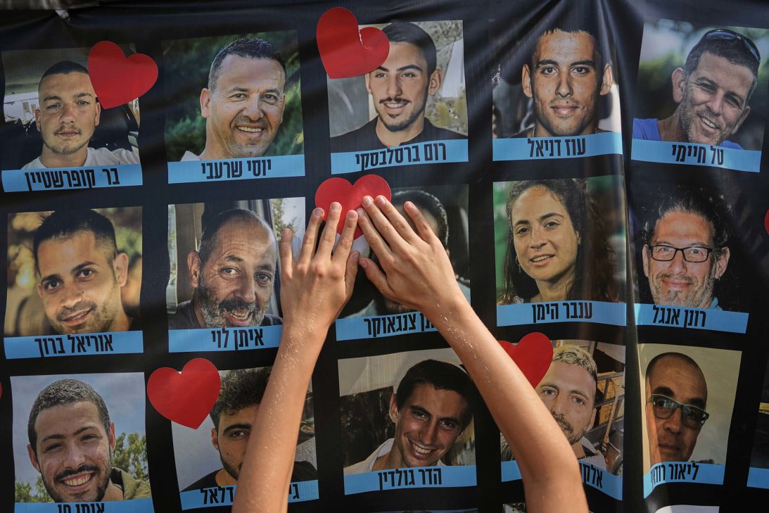 A person pastes a heart-shaped sticker on a banner with pictures of Israeli hostages during a gathering at Hostages Square in Tel Aviv, Israel, on Monday.