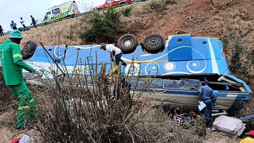 In this photo made available by the South African Department of Transport and Community Safety, Police officers and emergency rescue workers search for victims from a bus lying upside down in the embankment, in Louis Trichardt, South Africa, on Sunday, Oct. 12, 2025.