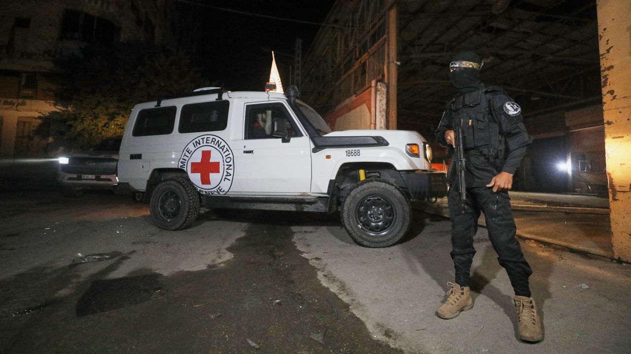 A gunman wearing the uniform of the al-Qassam Brigades, the military wing of Hamas, stands guard as Red Cross vehicles enter a warehouse allegedly to collect coffins containing the bodies of four deceased hostages, in Gaza City, Tuesday, Oct. 14, 2025. (AP Photo/Yousef Al Zanoun)