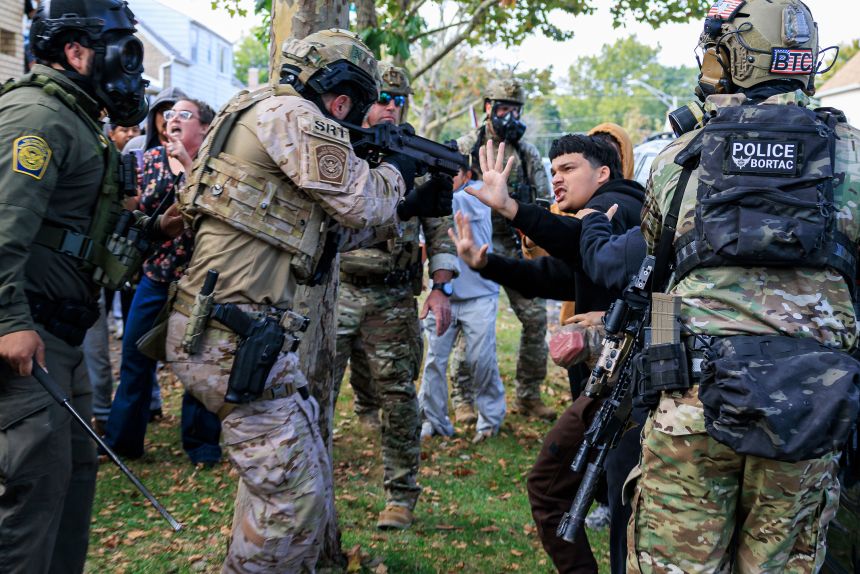 A law enforcement officer points a crowd control weapon at a protester in Chicago on Tuesday.