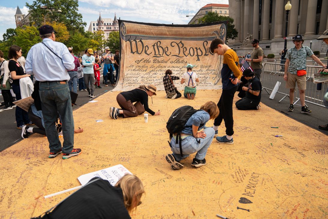 Attendees sign a banner representing the US Constitution during a "No Kings" protest in Washington, DC, on Saturday.