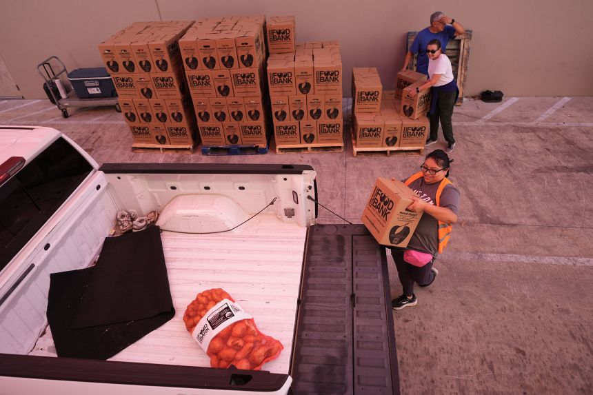 Volunteer Cindy Leiva, front right, helps load a vehicle as part of a food distribution effort targeting federal employee households affected by the federal shutdown as well as SNAP recipients on Monday in San Antonio.