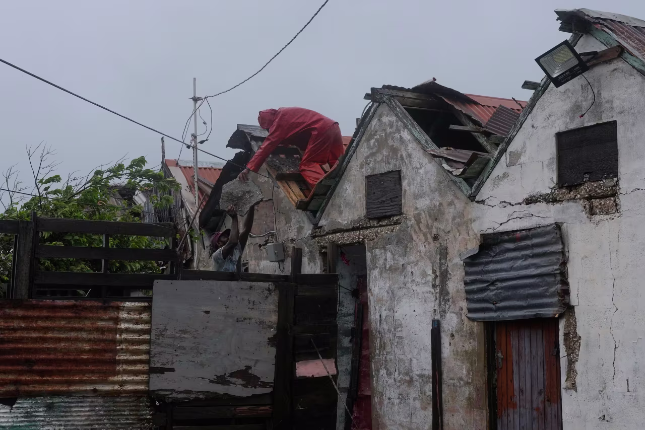 Men remove a loose section of roof in Kingston on Monday.
