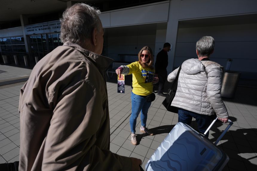 Air Traffic Controller Lisa Blake distributes a leaflet to travelers explaining how the federal government shutdown is impacting air travel at Detroit Metropolitan Wayne County Airport in Romulus, Mich on Tuesday.