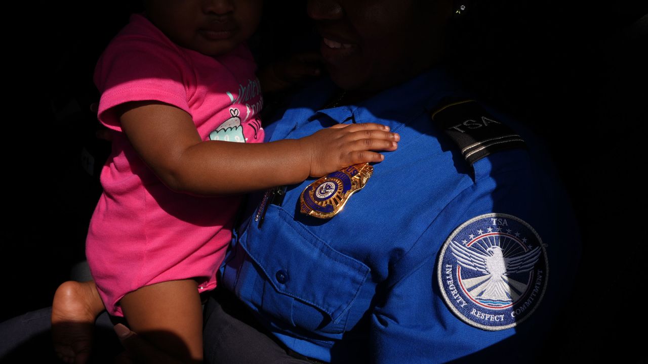 A TSA agent holds her daughter as she collects a donation of produce, meat and yogurt at a food distribution center organized to assist federal employees missing paychecks during the government shutdown, in Dania Beach, Florida, on October 28.