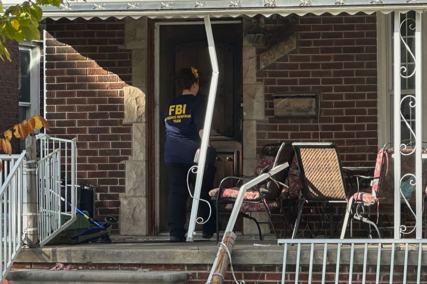 An FBI agent enters a home in a Dearborn, Michigan, neighborhood on Friday.