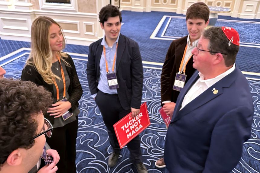 Florida State Sen. Randy Fine, right, speaks with college students, one of whom holds a sign saying