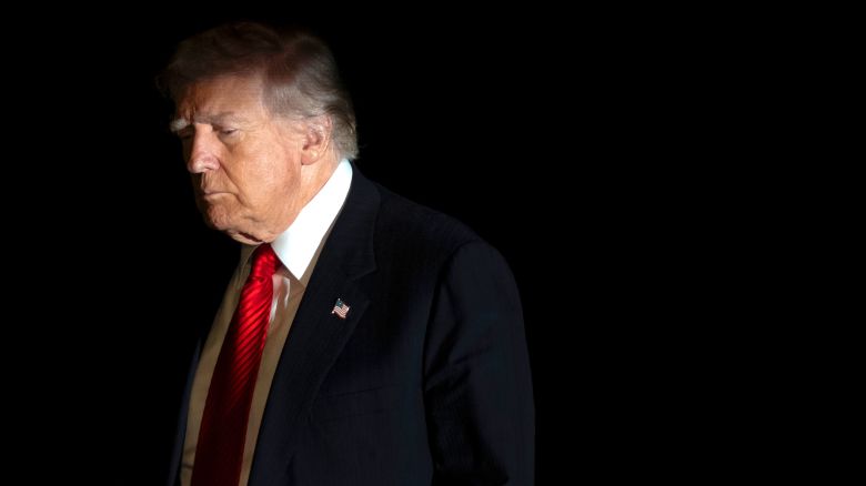 President Donald Trump is illuminated by a camera flash as he walks across the South Lawn of the White House, Sunday, Nov. 2, 2025, in Washington, after returning from a trip to Florida. (AP Photo/Mark Schiefelbein)
