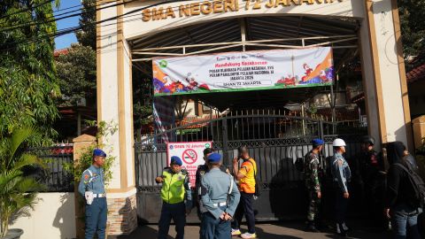 Police officers and military personnel stand guard at the gate of a school where explosions reportedly occurred, in Jakarta, Indonesia, Friday, Nov. 7, 2025.