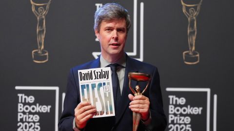 Hungarian-British author David Szalay poses for photographers with the trophy after winning the Booker Prize 2025 for his book 'Flesh' during a ceremony at Old Billingsgate in London, Monday, Nov. 10, 2025. (AP Photo/Kirsty Wigglesworth)