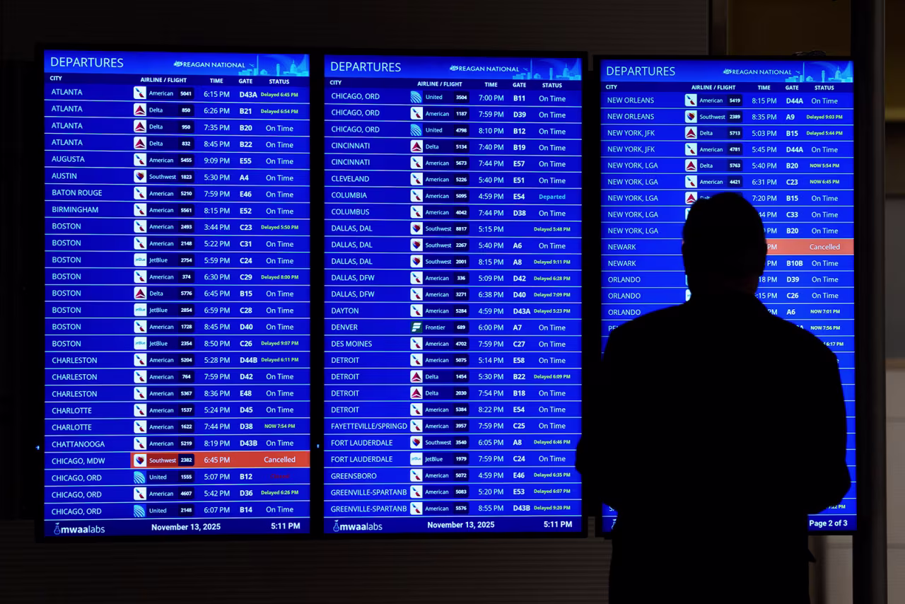 People look at a flight arrivals and departures board at Ronald Reagan National Airport on Thursday.