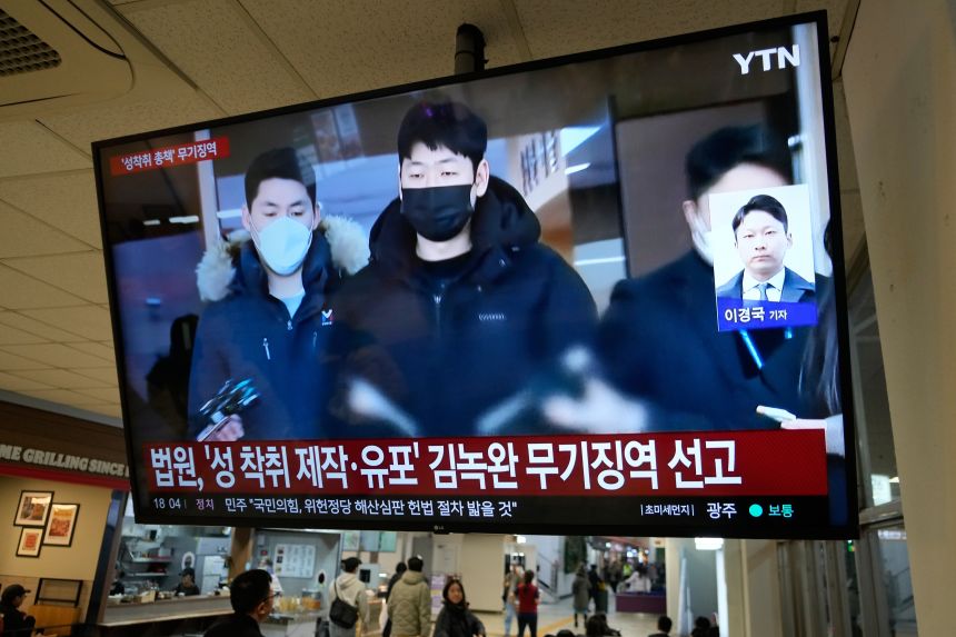 A television screen shows Kim Nok-wan (center), the leader of a Telegram-based sex crime ring, during a news program at a bus terminal in Seoul, South Korea on November 24, 2025.