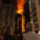 People look at flames engulfing a building after a fire broke out at Wang Fuk Court, a residential estate in the Tai Po district of Hong Kong's New Territories, Wednesday, Nov. 26 2025. (AP Photo/Chan Long Hei)