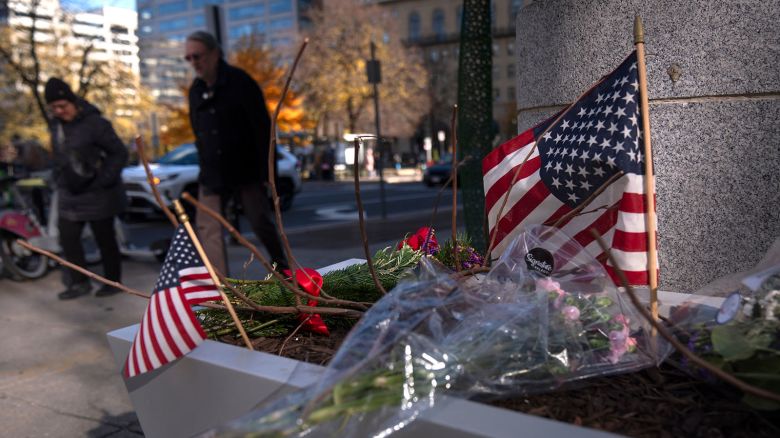 People walk past a small memorial in a planter on Friday, November 28, near the site where two National Guard members were shot in Washington, DC.