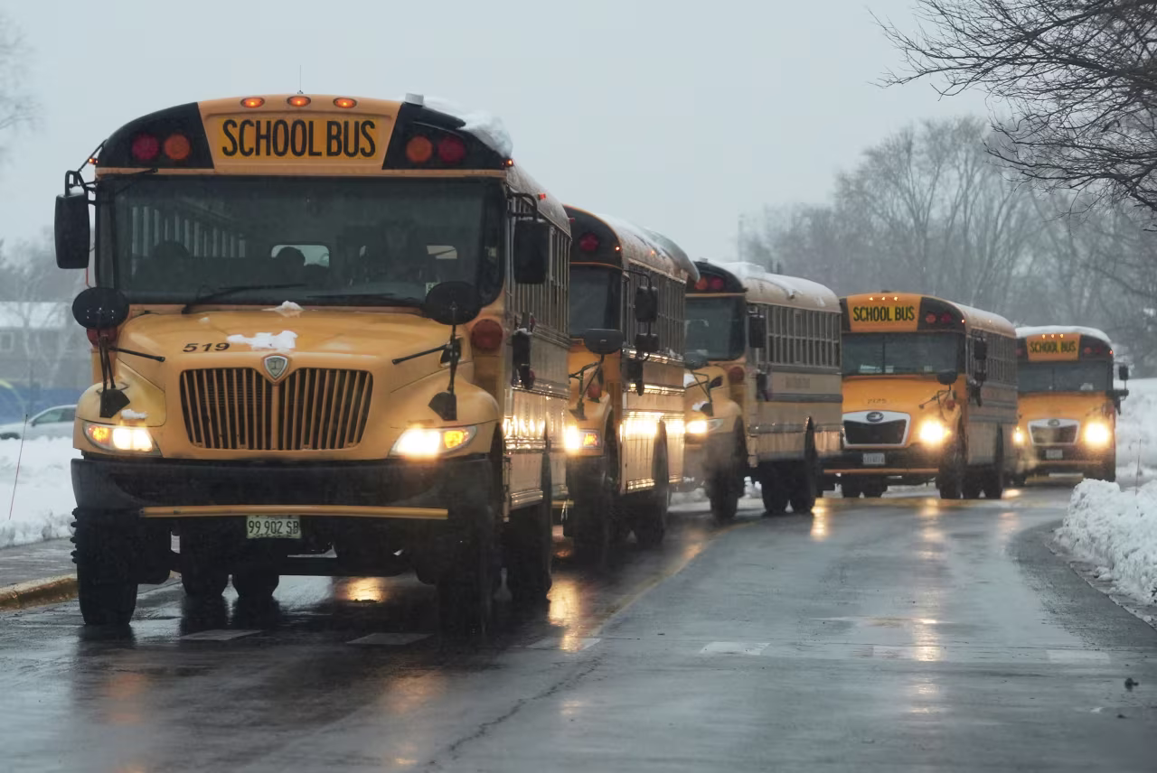 School buses are driven along a street in Wheeling, Illinois, on Monday.