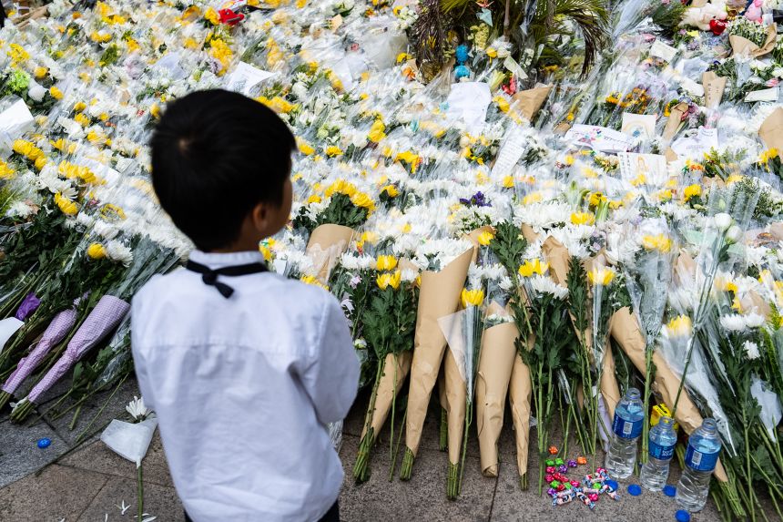 People offer flowers for the victims near the site of a deadly fire at Wang Fuk Court, a residential estate in the Tai Po district of Hong Kong, on December 2, 2025.