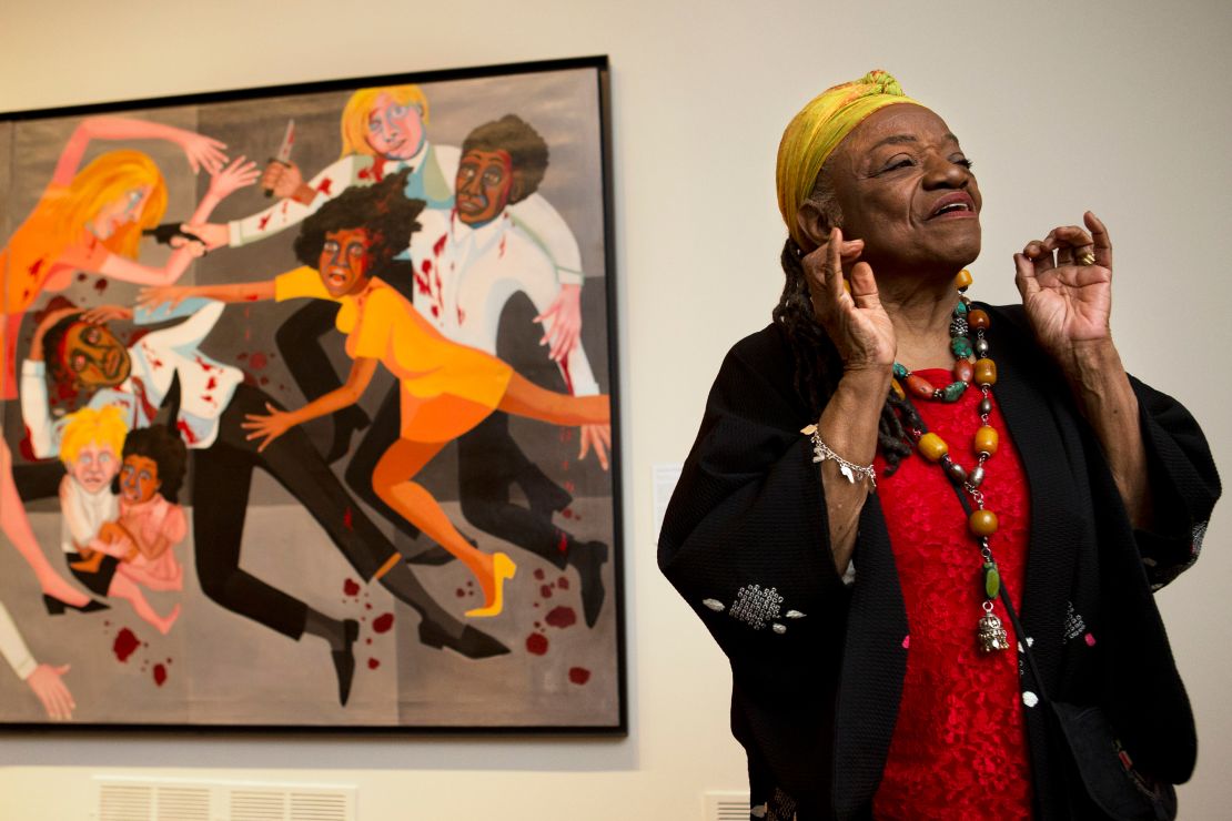 Faith Ringgold is pictured during a preview for a 2013 exhibition at the National Museum of Women in the Arts in Washington, D.C., with her 1967 painting "American People Series #20: Die" visible, in part, in the background. "I didn't want people to be able to look, and look away," Ringgold said at the preview. "I want them to look and see. I want to grab their eyes and hold them, because this is America."