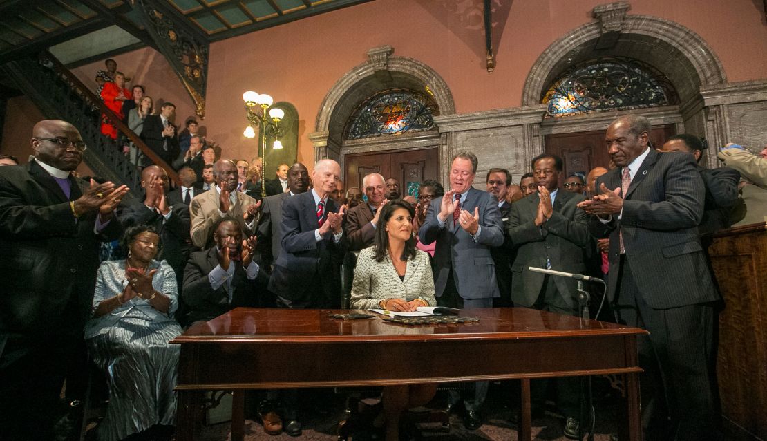 Haley, surrounded by three former governors, some family members of the slain nine, and many legislators, signing a bill to remove the Confederate flag from the Statehouse grounds on July 9, 2015.