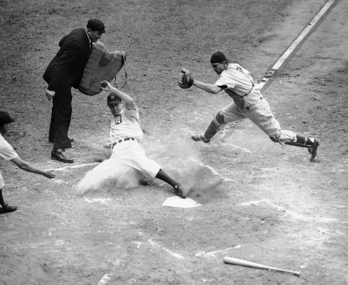 Hank Greenberg crosses the plate with the third run as Aaron Robinson makes a stab for him in July 1946.