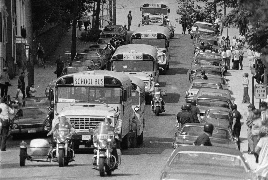 Motorcycle police escort school buses as they leave South Boston High School on the second day of court-ordered busing, September 14, 1974. Some buses were stoned by protesters, and police made several arrests.