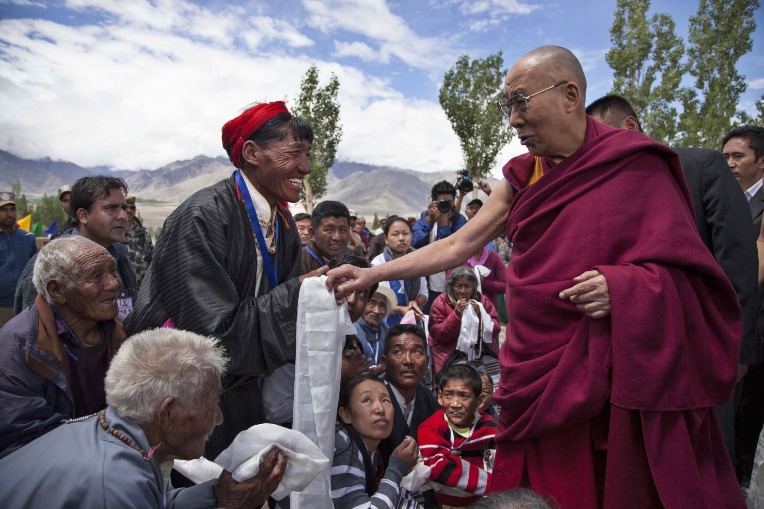 Tibetan spiritual leader the Dalai Lama talks to a Buddhist devotee as he arrives at the Tibetan children's village school near Leh, India, on July 2014.