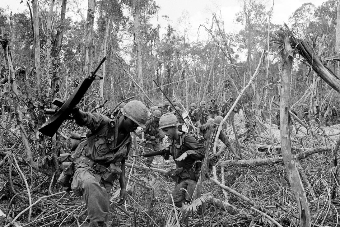 American troops of the 2nd Battalion of the 16th Infantry crawl through entangled roots and branches as they advance on suspected Viet Cong guerrilla nests near the Cambodian border in South Vietnam on May 4, 1966.