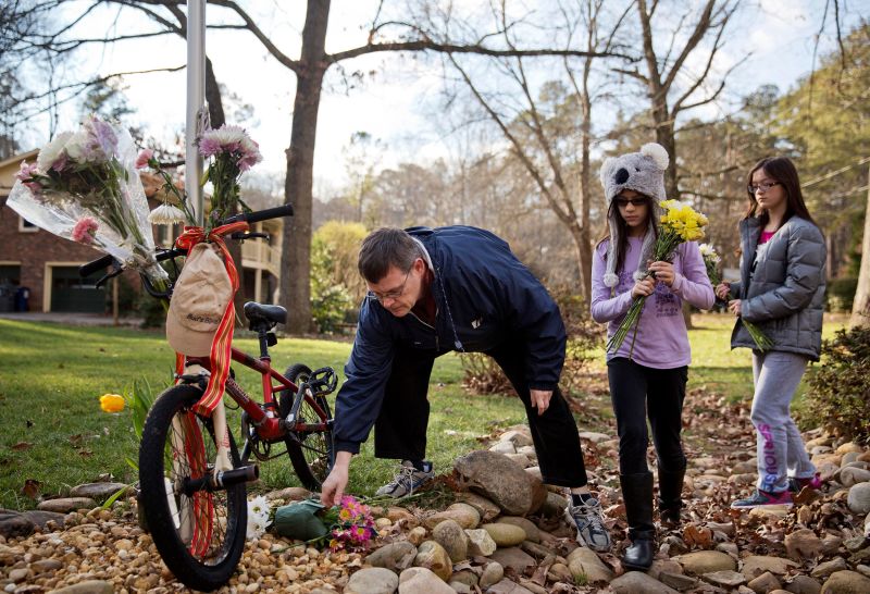 Jason Hoffman places flowers at a makeshift memorial outside the home of Elrey