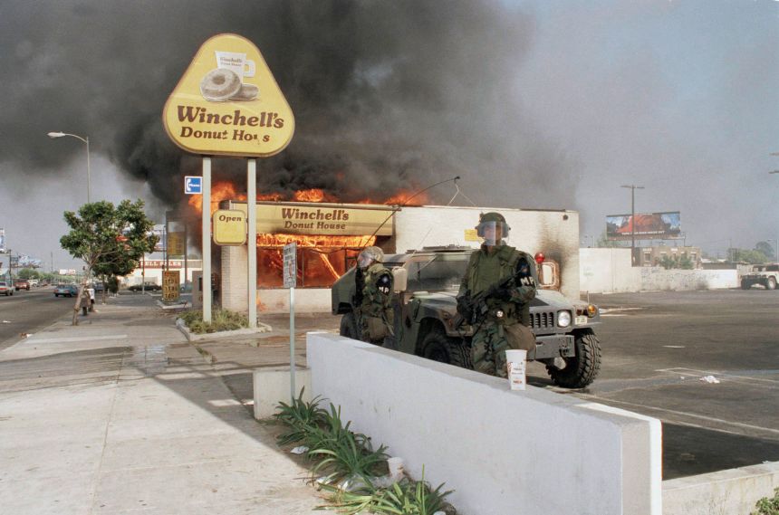 Two National guardsmen stand guard outside a burning donut shop in Los Angeles on April 30, 1992. The National Guard was called in to aid police during the second day of rioting in the city.