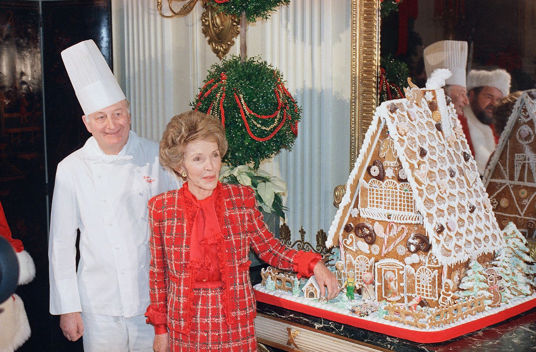 <strong>1987</strong>: Reagan (pictured with White House chef Hans Raffert) debuted the year's gingerbread house, which included a miniature version of her dog, Rex.