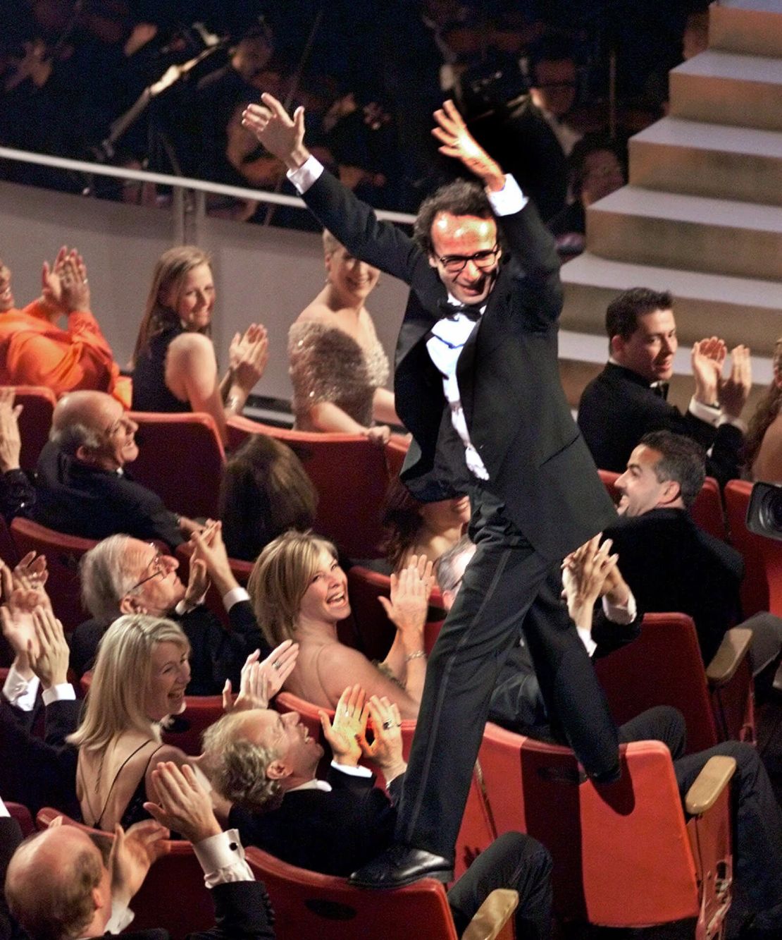 Director and actor Roberto Benigni jumps on the back of some chairs in excitement after winning the Oscar for best foreign language film for "Life is Beautiful" at the Oscars in 1999.
