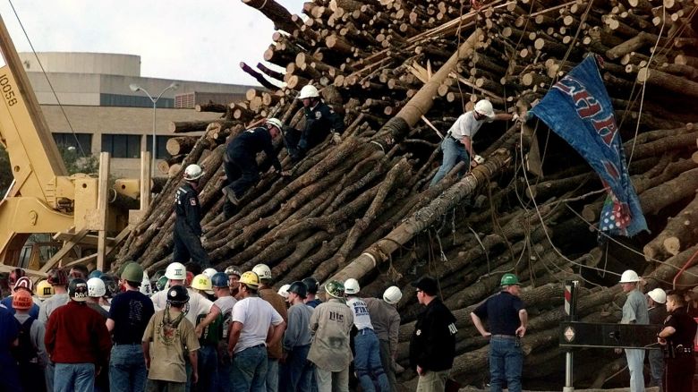 Texas A&M students and rescue workers gather at the base of the collapsed bonfire stack as the search continues for victims Thursday, Nov. 18, 1999, in College Station, Texas. The stacks' center pole, shown in two pieces, one carrying a Corps of Cadets squadron flag, and the second just above, apparently snapped and the stack collapsed. Ten students were killed along with one student graduate. (AP Photo/Pat Sullivan)