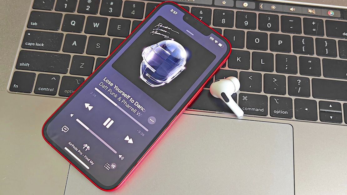 An AirPod Pro and an iPhone on a MacBook keyboard.