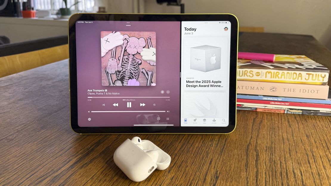 The iPad 11 shows the Clipse song Ace Trumpets is playing, airpods pro are in the foreground