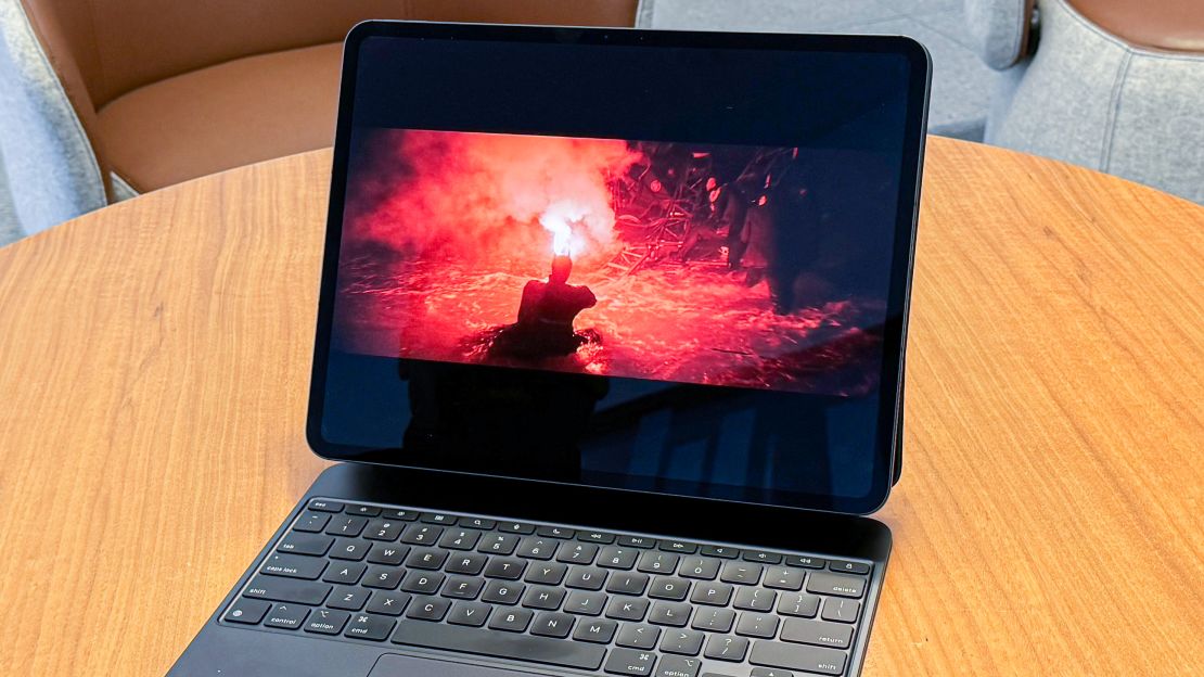 An iPad Pro M4 on its Magic Keyboard while the film "The Batman" plays with Batman using a red flare in a dark watery area.