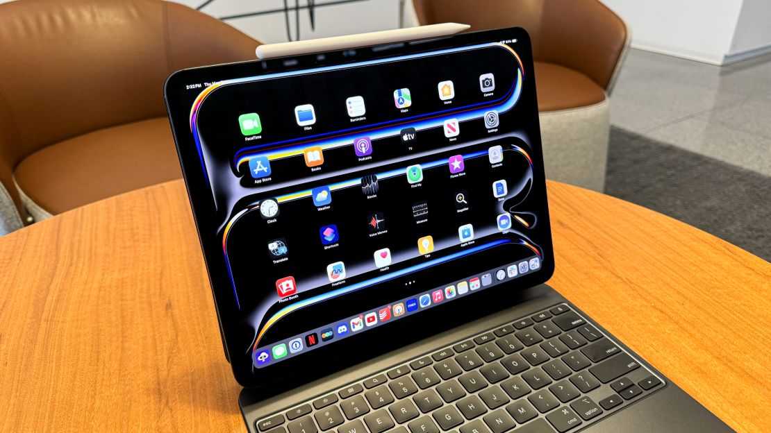 The Apple iPad Pro M4 open to home screen with icons sits on its Magic Keyboard with Apple Pencil Pro above it